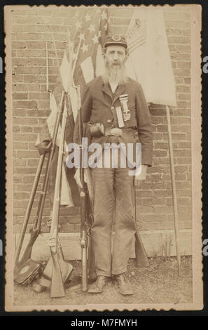 Nicht identifizierte Bürgerkriegveteran von der Grand Armee der Republik Post 386 in Uniform mit muskete vor Flaggen, Waffen und Ausrüstung LCCN 2016652272 Stockfoto