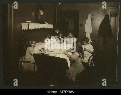 Dieses Foto, aufgenommen um 21:00 UHR im Haus von Patrick McGurl in Worcester, Mass., zeigt F. A. Smith, wie er an Schlauchhaltern arbeitet. Die Szene umfasst drei Kinder im Alter von 6, 8 und 11 Jahren, die das Werk beobachten. McGurl, ein Mechaniker, ist mit Reparaturen beschäftigt. Das Bild ist Teil einer historischen Sammlung der Library of Congress. Stockfoto