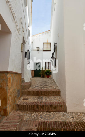 Suchen nach einem engen Spanischen Cul De Sac-Straße, zwischen der weiß getünchten Häusern, mit einem gepflasterten Gehsteig anzeigen Geometrische Muster. Stockfoto