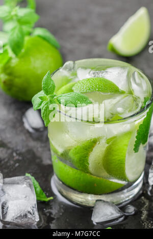 Kalt Erfrischende Sommer trinken mit Limette, Minze und Eiswürfel in einem Glas auf einem dunklen Stein Hintergrund. Mojito. Limonade. Detox. Mineralwasser. Selektive fo Stockfoto