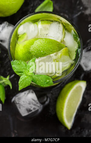 Kalt Erfrischende Sommer trinken mit Limette, Minze und Eiswürfel in einem Glas auf einem dunklen Stein Hintergrund. Mojito. Limonade. Detox. Mineralwasser. Selektive fo Stockfoto