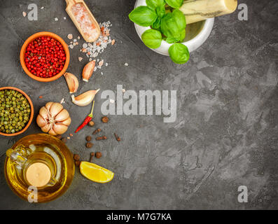Auswahl der Gewürze und Kräuter - Knoblauch, Salz, Rosa, Grün, Schwarz Pfeffer, Zitrone, Basilikum, Olivenöl. Zutaten zum Kochen. Essen Hintergrund auf Schwarz Stockfoto
