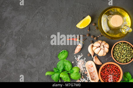 Auswahl der Gewürze und Kräuter - Knoblauch, Salz, Rosa, Grün, Schwarz Pfeffer, Zitrone, Basilikum, Olivenöl. Zutaten zum Kochen. Essen Hintergrund auf Schwarz Stockfoto