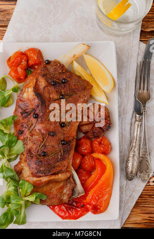Lamm, im Ofen gebacken mit Gewürzen - Rosmarin, Knoblauch und Wacholder. Tomaten, Paprika und Kräutern. Die gourmet Abendessen. Selektiver Fokus Stockfoto