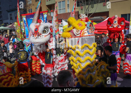 Zuschauer verfolgen Männer in drei bunten tanzenden Löwen Kostüme und Banner während eines Chinese New Year Parade und Feiern in San Diego, CA Pass Stockfoto