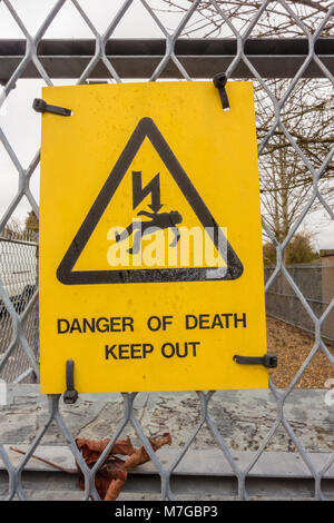Ein Schild auf dem Gitter Zaun eine elektrische Unterstation warnt vor der Gefahr von Tod durch Stromschlag, die von der elektrischen Ausrüstung gestellt. Stockfoto