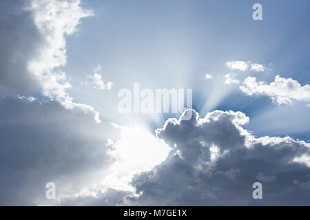 Sonnenstrahlen aus hinter Wolken in hell Blau skyninspiring Stockfoto