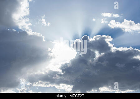 Sonnenstrahlen aus hinter Wolken in hell Blau skyninspiring Stockfoto