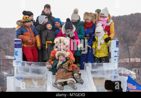 Hatgal, Mongolei, 4. März 2018: mongolische Kinder in traditioneller Kleidung auf einem zugefrorenen See Khuvsgul, unten kommen, eine Folie madeout von Eis Stockfoto