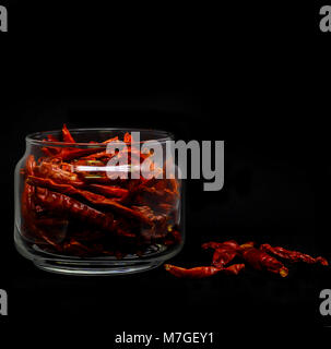 Getrocknete rote Chili in Glas Container in schwarzer Hintergrund Stockfoto