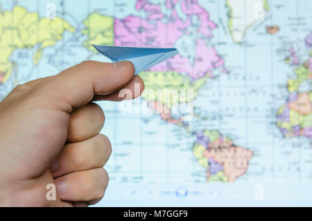 Foto von der Hand des Menschen holding Spielzeug Papierflieger gegen Karte der Welt. Bild ist retro gefiltert Stockfoto