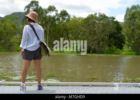 Frau blickt über einen Fluss, Apex Park, Riverway Drive, Condon, QLD, Australien Stockfoto