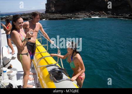 Eine Gruppe von jungen Leuten (MR) auf einen harten Boden aufblasbar aus Schnorcheln Lanai, Hawaii zurück. Stockfoto