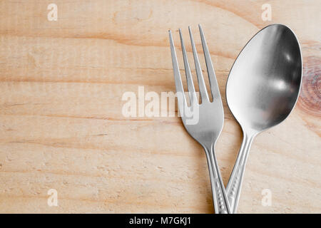 Edelstahl Löffel und Gabel auf hölzernen Tisch Stockfoto