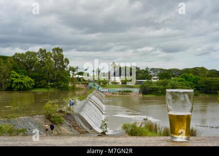 Ein Bier trinken mit Blick auf Wasser überlaufen der Wehr nach neuen schweren Regen, Riverview Taverne in Douglas Townsville Queensland Australien Stockfoto