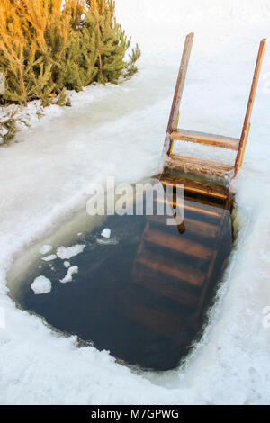 Epiphanie Loch mit einer Holztreppe im Winter schwimmen im Fluss Stockfoto