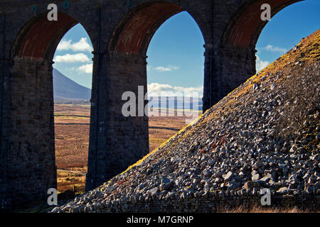 An der Unterseite der Whernside: Blick durch die Bögen der Ribblehead Viadukt, mit Geröll an der Unterseite der Whernside im Vordergrund. Stockfoto