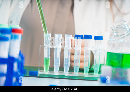 Junge Frau im wissenschaftlichen Labor mit Pipette und Chemikalien in den Reagenzgläsern Stockfoto