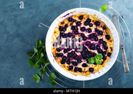 Quark Auflauf gebacken mit Heidelbeeren. Quark Auflauf mit frischen Beeren am Küchentisch. Ansicht von oben Stockfoto