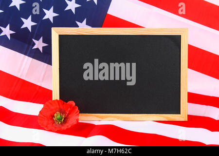 Schwarzes Brett auf der amerikanischen Flagge und einer Mohnblüte Hintergrund. Stockfoto