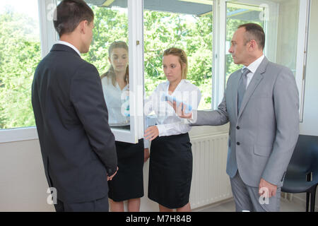 Auszubildende, die Reinigung eines Spiegels unter Aufsicht Stockfoto