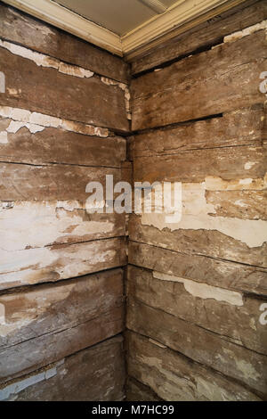 Stapeln Holzbalken und Brocken von weißem Putz auf die Wände in einem Zimmer in einem alten 1800s Cottage Stil Stück sur Stück log home. Stockfoto