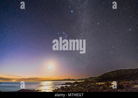 Er waxing Crescent Moon und Orion Einstellung in die Dämmerung von Cape Conran, Australien. Stockfoto