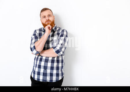 Portrait von gutaussehenden jungen Mann mit dem roten Haar und Bart in Plaid Shirt gegen weiße Wand Stockfoto