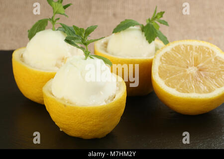 Frische Zitronensorbet in halbierte Zitronen mit Minze garnieren serviert. Stockfoto