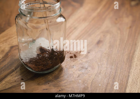 Die Kakao Getränk in Glas Glas mit Griff auf Holz Tisch, das Hinzufügen von Wasser, flacher Fokus Stockfoto