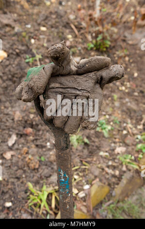 Folgen der Gartenarbeit in extrem schweren Lehm lehmiger Erde, schwere Gartenarbeit Gabel in Erde bedeckt und Schlammigen, schmutzige zusammengebacken in Schlamm Schlamm Stockfoto