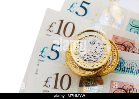 Stapel von neuen 12-seitigen englischen ein-Pfund-Münzen £ Pfund Sterling uk Geld Bargeld auf neue Polymer-Kunststoff £10 und £5 Banknoten GBP close-up. England Großbritannien Stockfoto