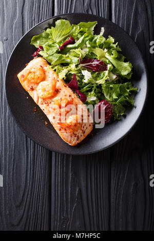 Gebackenen Lachs mit Krabben und Honig Sauce mit Beilage Salat mix Close-up auf einem Teller auf dem Tisch. Vertikal oben Ansicht von oben Stockfoto