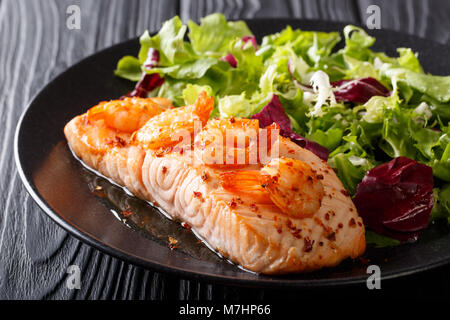 Gebackenes Lachsfilet mit Garnelen und Cayenne Pfeffer und frischem Salat auf einen Teller close-up auf einem Tisch. Horizontale Stockfoto