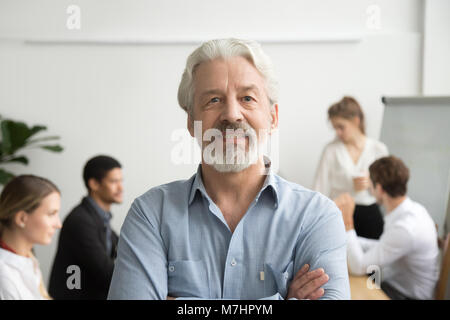 Zuversichtlich älterer Geschäftsmann Leader bei Kamera suchen, Team b Stockfoto