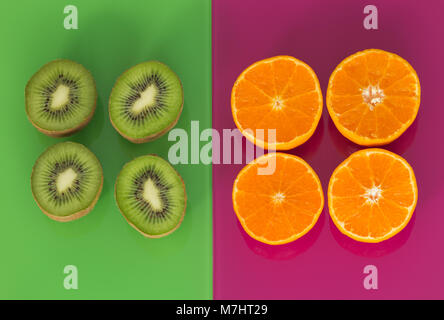 Kiwi und orange Früchte auf grün-violett Glas Hintergrund Stockfoto