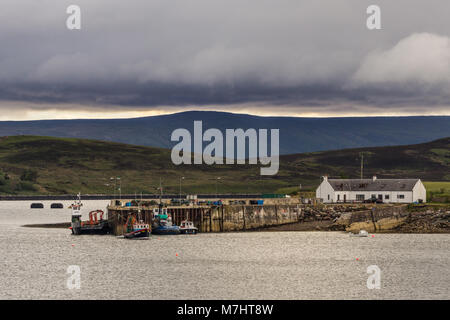 Nach Aultbea, Schottland - Juni 8, 2012: ruhiges Wasser von Loch Ewe mit dem Pier und den Hafen von Aultbea unter dunklen regnerischen cloudscape. Dunkle Hügel im Hintergrund. Stockfoto