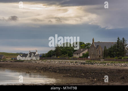 Nach Aultbea, Schottland - Juni 8, 2012: ruhiges Wasser von Loch Ewe mit dem Community Center von Aultbea unter dunklen regnerischen cloudscape. Straße mit weißen Haus. Stockfoto