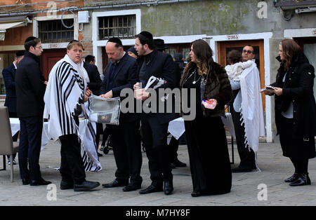 Venedig, Italien. 10. Mär 2018. Mitglieder der jüdischen Gemeinschaft in der Campo del Ghetto Nuovo, während der Sabbat feiern, Tag des Israel Gemeinschaft feiern in Venedig. Das Campo del Ghetto Nuovo in Venedig, im Viertel Cannaregio befindet. Der Campo del Ghetto Nuovo ist das wahre Zentrum der Jüdischen Ghetto von Venedig. Dieses Ghetto war der erste in der Welt und hat seinen Namen von einem bestehenden Gießerei, wo sie geschmolzen oder "warf" der Metalle für den Schiffbau im Arsenal benötigt. Daher auch der Name "Jet" und "Ghetto", in der jeder erkennt jetzt, ein Ort der Trennung. Stockfoto