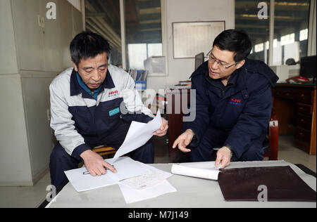(180311) - Peking, 11. März 2018 (Xinhua) - Mi Zhongyi (L), der neu gewählte Stellvertreter des 13. Nationalen Volkskongress (NVK), diskutiert mit seinem Kollegen an einem Workshop von Übertragungstechnik Unternehmen der Nördlichen Heavy Industries Group Co., Ltd. in Shenyang, Provinz Liaoning im Nordosten Chinas, Feb 23, 2018. Mi Zhongyi ist ein Arbeiter am Getriebe Equipment Company des Nördlichen Heavy Industries Group Co., Ltd. in Shenyang. Er hat sich an die Arbeit, als er das erste Mal die Firma im Jahr 1983 beigetreten sind. Jahre der Praxis und Studium haben ihn zu einem Senior Techniker gedreht. Ein Dutzend seiner App Stockfoto