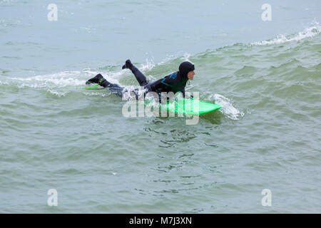 Bournemouth, Dorset, Großbritannien. 11. März 2018. UK Wetter: Grau bewölkten Tag in Bournemouth Strände als Besucher auf dem Meer für Muttertag. SurferCredit: Carolyn Jenkins/Alamy leben Nachrichten Stockfoto