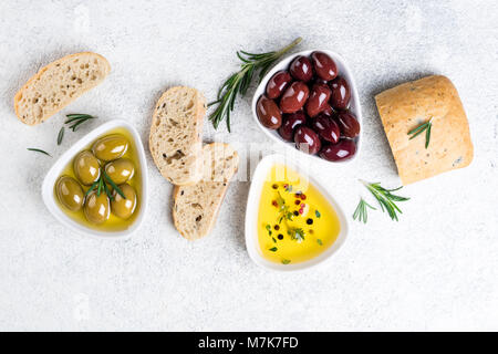 Mediterrane Snacks. Ciabatta Brot, Oliven, Öl, Kräutern und Gewürzen auf weißem Hintergrund. Ansicht von oben Stockfoto
