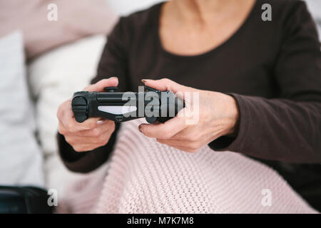 Eine ältere Frau spielt ein Video Spiel. Ältere person und moderner Technologie. Stockfoto