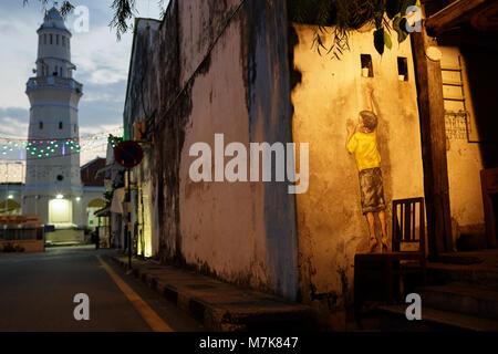 Georgetown Penang am Abend, Wandbild Street Art Junge auf dem Stuhl Stockfoto