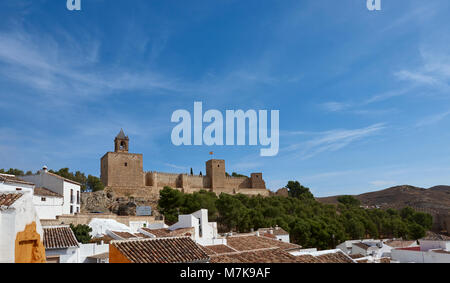 Die Alcazaba von Antequera, Stolz unter spanischer Flagge, dominiert die Skyline über den Dächern und Terrassen dieser Stadt in Andalusien. Stockfoto