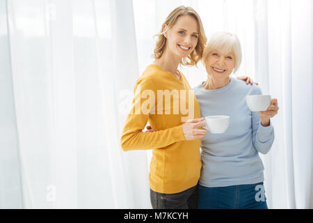 Positive cute Verwandten umarmen und lächelnd während Sie Ihren Kaffee Trinken Stockfoto