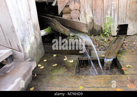 Frühling mit sauberem Trinkwasser, angepasst, um Wasser von einem hölzernen Trog zu sammeln. Stockfoto