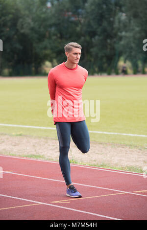 Junge Athlet Mann Entspannen und Strech Bereit für Laufen bei Leichtathletik Rennstrecke auf Stadium Stockfoto