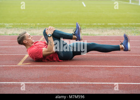 Junge Athlet Mann Entspannen und Strech Bereit für Laufen bei Leichtathletik Rennstrecke auf Stadium Stockfoto