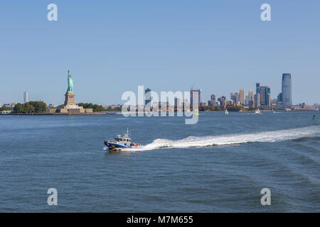 New York, USA - 26. August 2017: NYPD Boot patrouillieren East River. Im Hintergrund Blick auf die Freiheitsstatue und New Jersey Wolkenkratzer. Summe Stockfoto